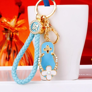 Detail of blue woven keychain with rhinestone flip-flop charm and golden coin pendant