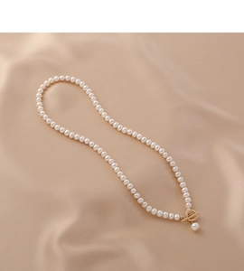 Detail of freshwater pearl necklace with gold OT clasp and rhinestone pendant on silk