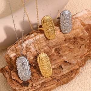Detail of vintage 18K gold and silver necklaces with oval floral relief and sawtooth edges