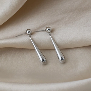 Gros plan détaillé de boucles d'oreilles en acier inoxydable sur un fond de soie beige