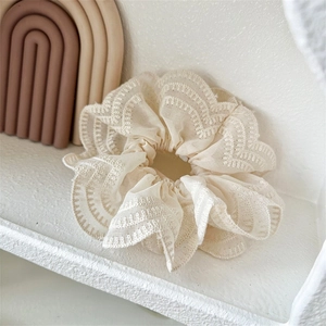 Gros plan d'un chouchou en dentelle beige montrant la texture fine et les volants