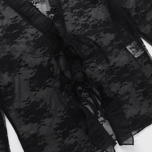 Détail de la dentelle noire semi-transparente avec motifs floraux sur le cardigan