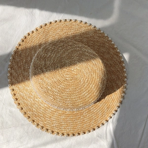 Detailed top view of a woven straw hat featuring elegant white pearl bead decorations