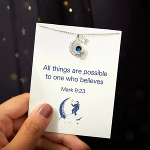 Detail of s925 silver astronaut moon necklace with blue stone on a quote card