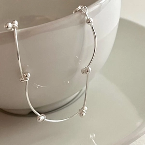 Minimalist S925 sterling silver beaded bracelet draped on a white ceramic cup