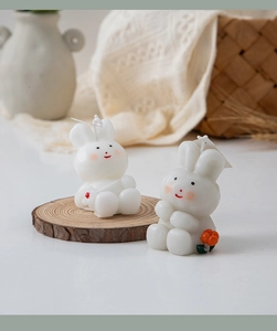 Detailed view of two cute white rabbit scented candles on a rustic wooden base