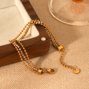 Three-layer gold stainless steel bracelet with zircon stones on a brown jewelry box