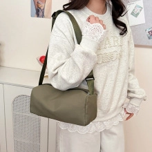 Bolso cilíndrico acolchado verde oliva mostrado por una modelo en un entorno interior