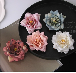 Detail view of five fabric floral hair clips in pink, blue, white, burgundy on book