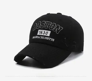 Detailed view of white Boston 1630 embroidery on distressed black cotton baseball cap