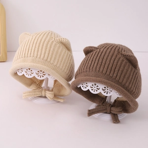 Dettaglio dei cappellini lavorati a maglia per neonati beige e marroni con orecchie