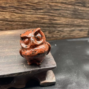 Detailed close-up of a 3.5cm hand-carved red jasper owl figurine on a dark wooden base