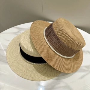 Elegant French boater straw hats with pearl ribbon decoration on white marble background