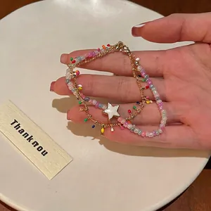 Close-up of colorful beaded bracelet with gold chain and white star pendant detail