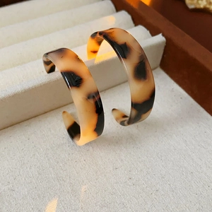 Detailed shot of leopard print C-shape resin hoop earrings on a beige velvet jewelry tray