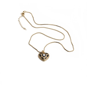 Détail macro d'un collier pendentif cœur doré avec œil de démon noir et fermoir mousqueton