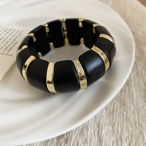 Detailed macro of matte black acrylic beads with polished gold spacers on elastic band