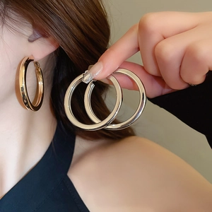 Polished oversized hoop earrings in gold and silver finish shown on a model