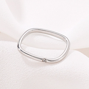 Macro shot of silver square ring featuring a single diamond on white fabric