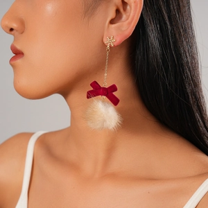 Detail of snowflake pendant earrings with red bow and beige fur ball on a model