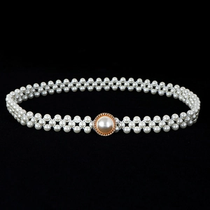 Macro detail of double-row pearl waist belt with gold round buckle on black background