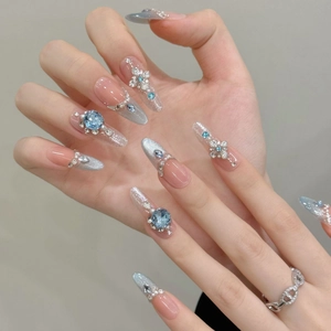 Detailansicht handgefertigter Kunstnägel mit blauen Kristallen und Silber-Glitzer-Verlauf