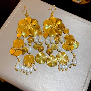 Makroaufnahme goldener Blumenohrringe mit gestuften weißen Perlenquasten auf Schmucktablett