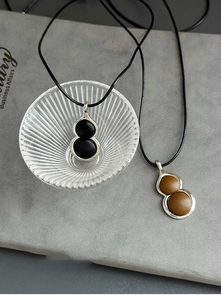 Close-up of black and brown resin gourd pendants with silver metal frames and cords
