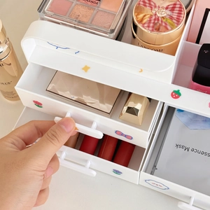 Detail view of a hand opening a white multi-layer plastic makeup storage box with cute stickers