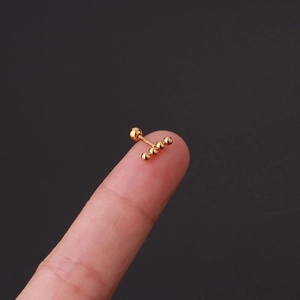 Detailed view of a gold screw-back cartilage stud with four beads on a fingertip