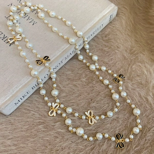 Detail showing the French style bow and pearl necklace layered on a vintage book
