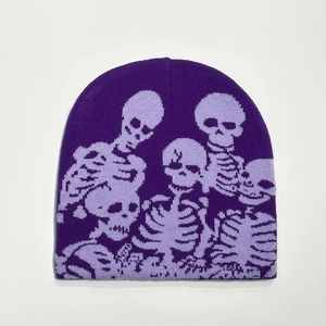 Detail of purple knitted beanie featuring multiple skull patterns on soft fabric