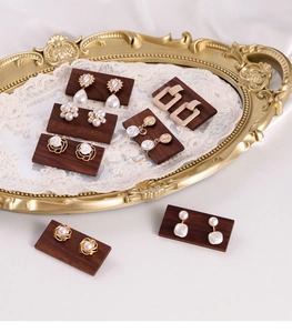 Detailed view of vintage gold pearl earrings on dark walnut wood display blocks