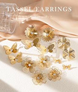 Detailed shot of golden floral and butterfly earrings with clear zircons on satin