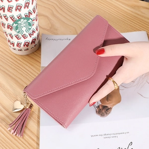 Dusty rose leather long envelope wallet with heart charm and tassel on wooden table