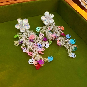 Vue détaillée de boucles d'oreilles fleur avec pompons en perles smiley colorées sur velours