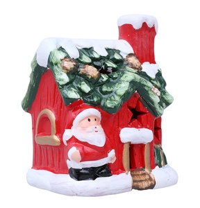 Detail of ceramic Christmas house with LED stars, Santa figure and snow coating