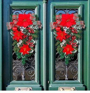 Close-up of symmetric Christmas door swags with red poinsettias and plaid ribbon bows