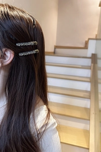 Detailed view of two dark grey hair clips with sparkling rhinestones on long hair