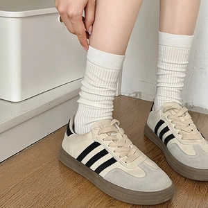 Chic beige and black striped retro sneakers styled with white ribbed cotton crew socks