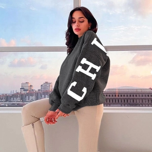 Détail d'un sweat gris oversize avec imprimé lettres CHI blanches et épaules tombantes élégantes
