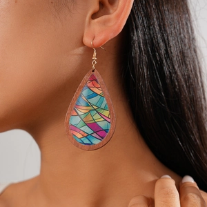 Close-up of Bohemian wood and acrylic teardrop earring worn by a model