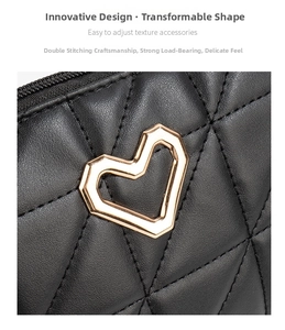 Close-up of heart-shaped gold metal buckle and quilted stitching on a black crossbody bag