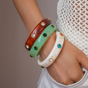 Detail of stacked acrylic resin bangles with inset colorful rhinestones on model