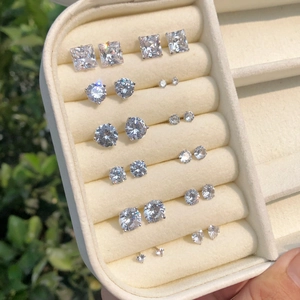 Macro view of various sized round and square cubic zirconia stud earrings in a beige case