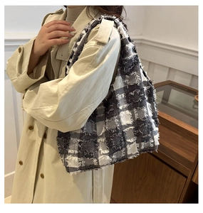 Detail of the oversized checkered tote bag with fringed edges on a model's shoulder