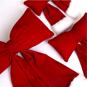 Close-up of red velvet Christmas bows and plush santa hat decorations on white background