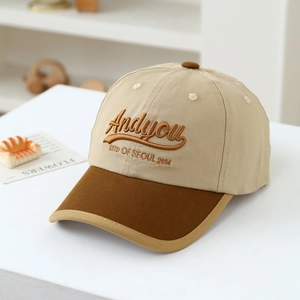 Dettaglio del ricamo 'Andyou' su cappello da baseball in tela cachi e marrone per bambini