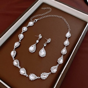 Macro detail of silver-toned necklace set with teardrop crystals in a brown gift box