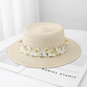 Detailed texture of woven straw boater hat with green floral chiffon ribbon decoration